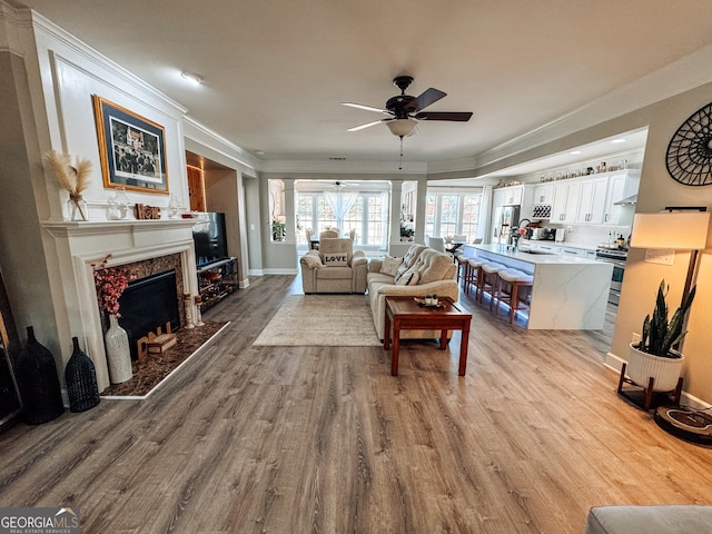 living area featuring ceiling fan, a high end fireplace, crown molding, and wood finished floors
