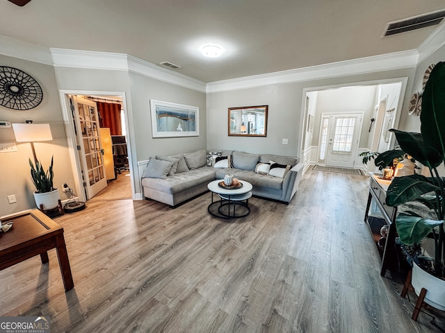 living room featuring visible vents, crown molding, and wood finished floors