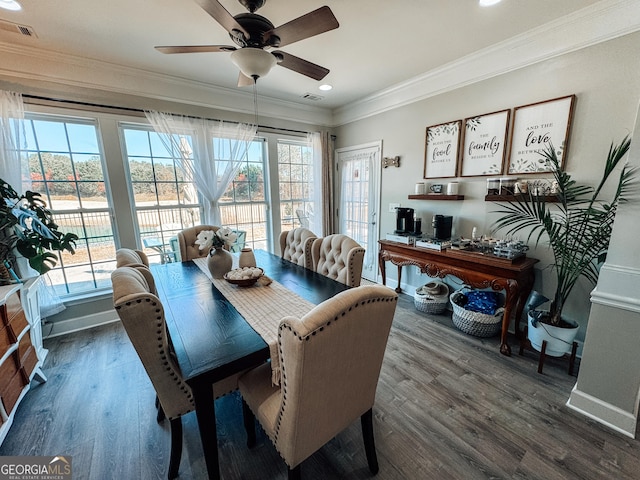 dining room featuring baseboards, wood finished floors, visible vents, and crown molding