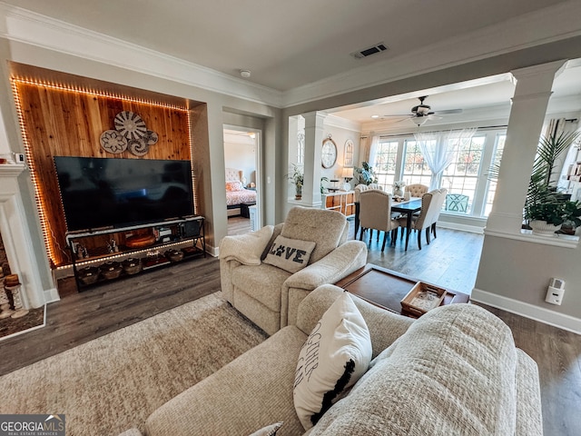 living room featuring crown molding, ornate columns, visible vents, wood finished floors, and baseboards