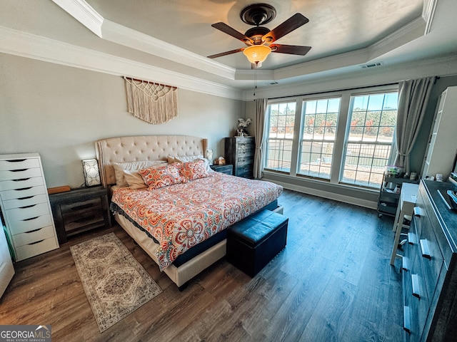 bedroom featuring crown molding, visible vents, a tray ceiling, and dark wood-type flooring
