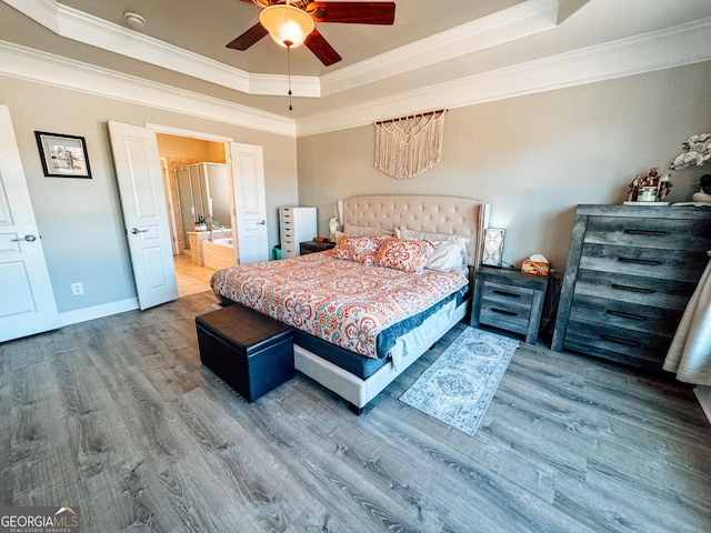 bedroom with a tray ceiling, wood finished floors, and crown molding
