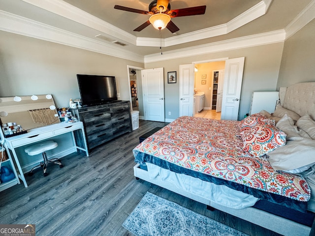 bedroom with a ceiling fan, crown molding, a tray ceiling, and wood finished floors