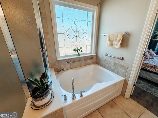 ensuite bathroom with connected bathroom, a shower with shower door, a garden tub, and plenty of natural light
