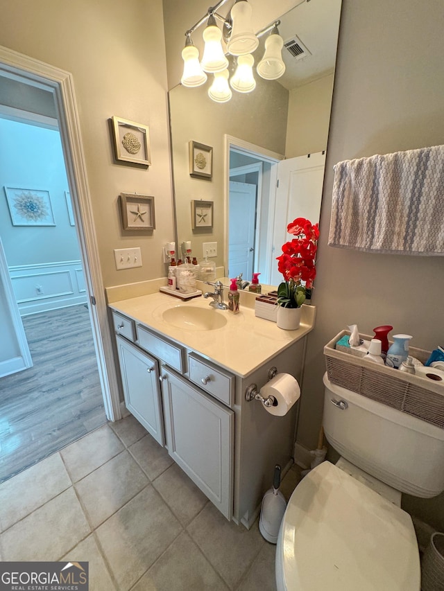bathroom with tile patterned flooring, toilet, vanity, visible vents, and an inviting chandelier