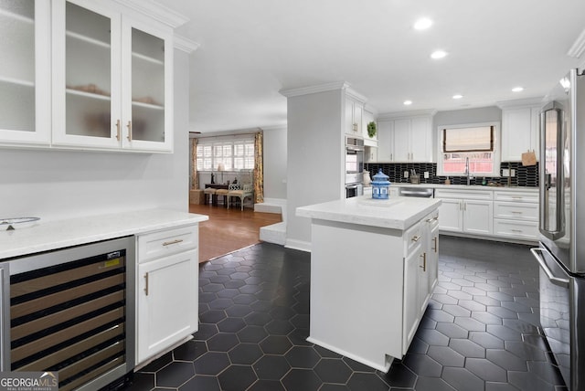 kitchen with wine cooler, stainless steel appliances, dark tile patterned floors, white cabinets, and backsplash