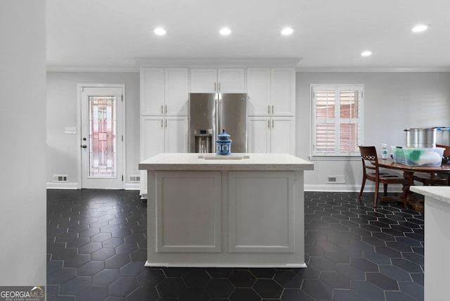 kitchen with crown molding, stainless steel refrigerator with ice dispenser, light countertops, visible vents, and white cabinetry