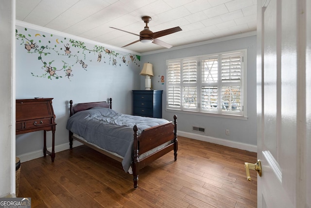 bedroom with baseboards, visible vents, hardwood / wood-style floors, and ornamental molding