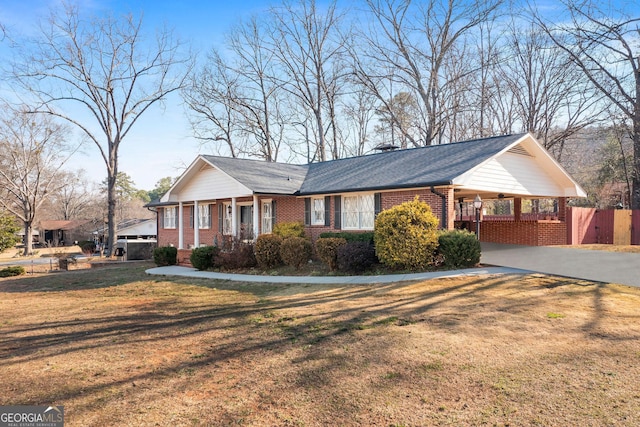 view of front of home featuring driveway, brick siding, a front yard, and fence