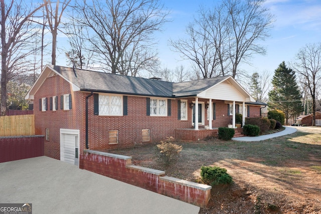 ranch-style house with covered porch, fence, and brick siding