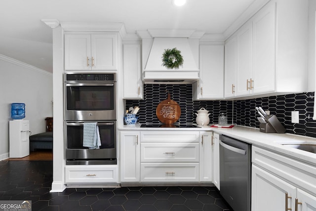 kitchen featuring white cabinets, light countertops, ornamental molding, appliances with stainless steel finishes, and tasteful backsplash