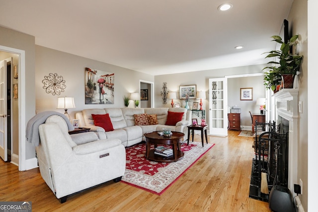 living room with light wood-style floors, recessed lighting, a fireplace, and french doors