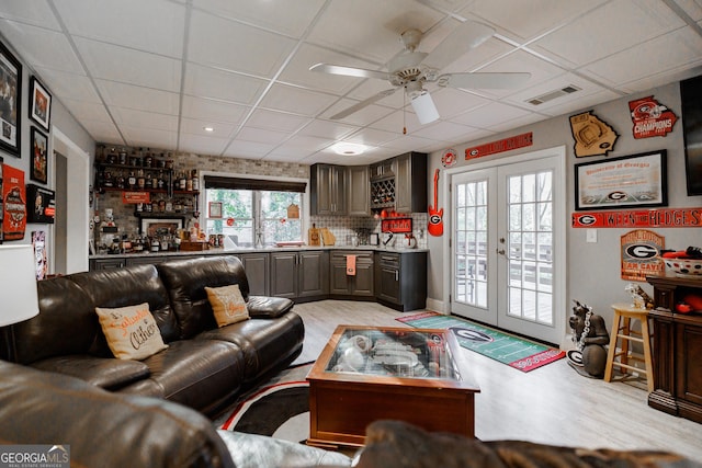 living area with light wood-style floors, french doors, visible vents, and a drop ceiling