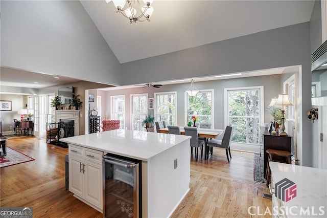 kitchen with a fireplace, light countertops, light wood-style floors, open floor plan, and beverage cooler