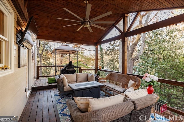 wooden deck featuring a gazebo, an outdoor living space, and a ceiling fan