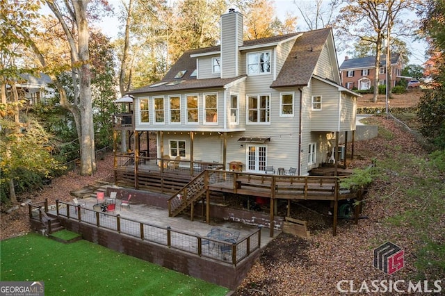 back of house with french doors, stairway, a wooden deck, a chimney, and a patio area