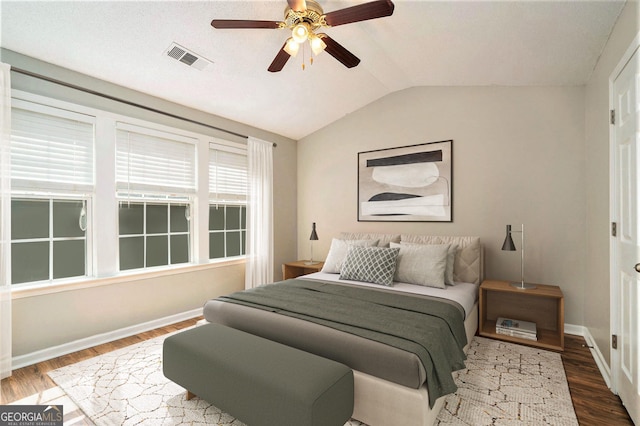 bedroom with baseboards, visible vents, vaulted ceiling, and wood finished floors