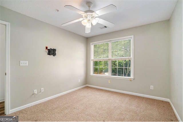 unfurnished room featuring carpet floors, visible vents, baseboards, and a ceiling fan