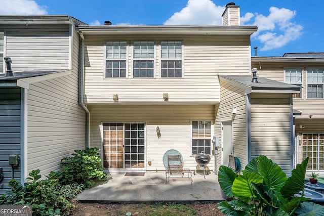 back of property featuring a chimney and a patio