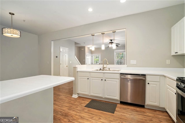 kitchen featuring light wood-style flooring, a sink, white cabinetry, hanging light fixtures, and appliances with stainless steel finishes