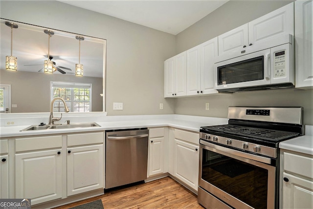 kitchen featuring stainless steel appliances, a sink, white cabinetry, and light wood-style floors