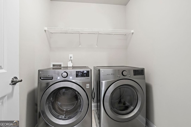 washroom with laundry area, washing machine and dryer, and baseboards