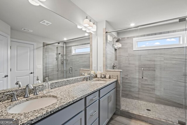 bathroom with double vanity, a sink, visible vents, and a shower stall