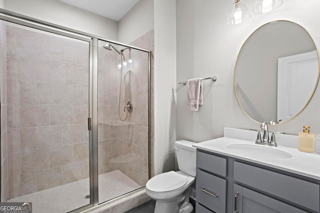 bathroom with toilet, a shower stall, and vanity