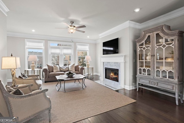 living area with recessed lighting, wood finished floors, a ceiling fan, a high end fireplace, and crown molding