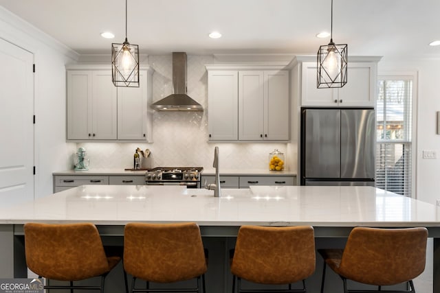 kitchen with decorative light fixtures, backsplash, appliances with stainless steel finishes, a sink, and wall chimney exhaust hood