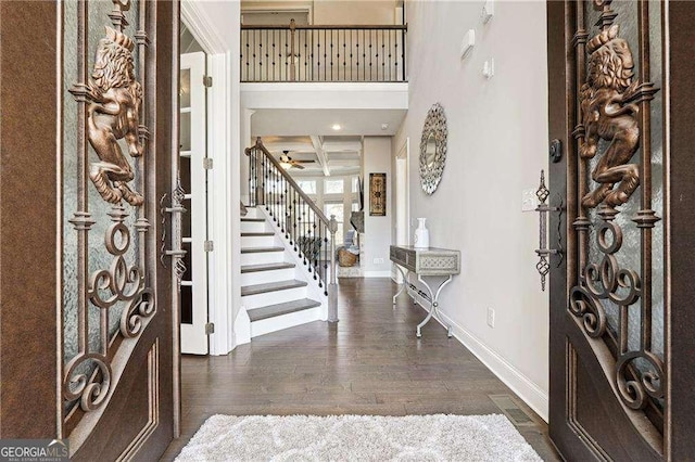 foyer featuring beam ceiling, stairway, wood finished floors, coffered ceiling, and baseboards