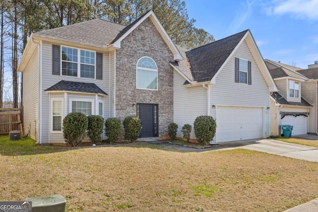traditional-style house featuring a shingled roof, an attached garage, a front yard, fence, and driveway