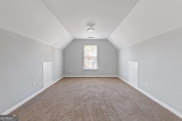 additional living space featuring carpet flooring, vaulted ceiling, visible vents, and baseboards