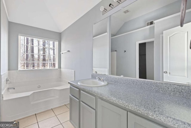 bathroom with visible vents, vaulted ceiling, vanity, tile patterned flooring, and a bath