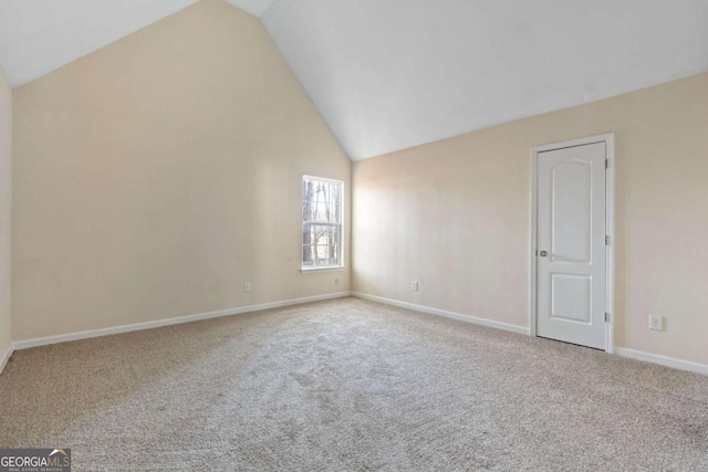 carpeted spare room with high vaulted ceiling and baseboards