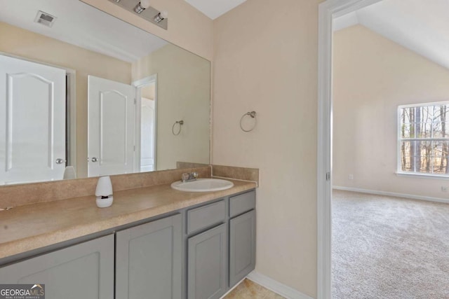 bathroom featuring vaulted ceiling, vanity, visible vents, and baseboards
