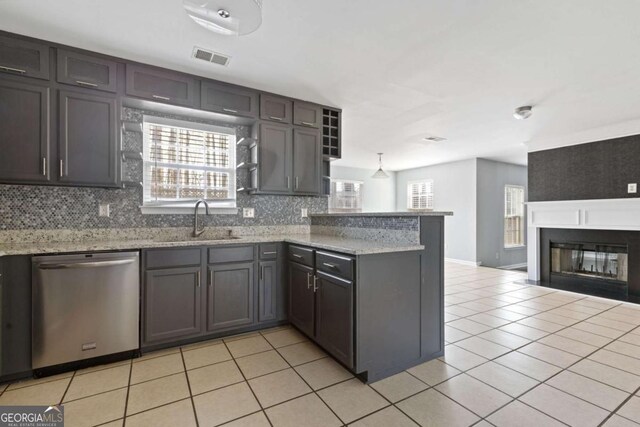 kitchen featuring light tile patterned floors, a peninsula, a sink, decorative backsplash, and dishwasher