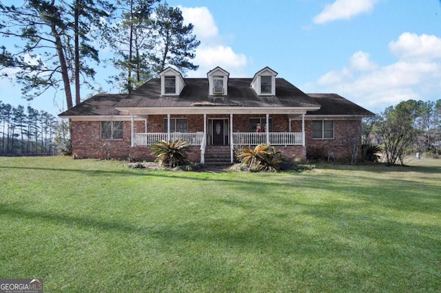 cape cod home with covered porch, a front lawn, and brick siding