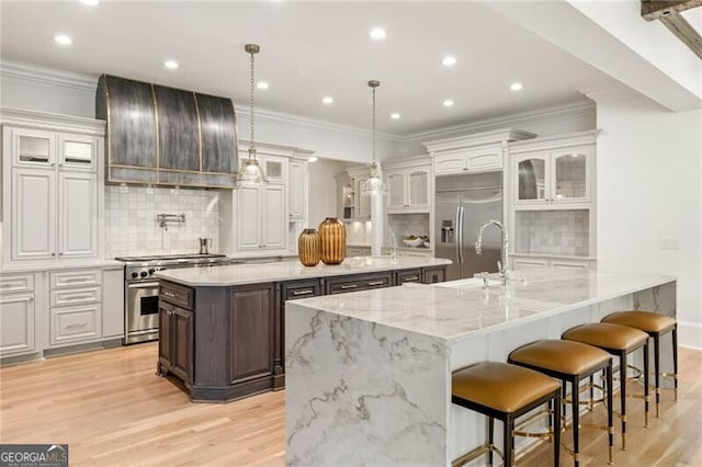 kitchen with a large island, high end appliances, custom exhaust hood, and light wood-style flooring