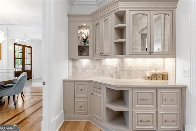 bar featuring tasteful backsplash, french doors, light wood-style floors, and crown molding