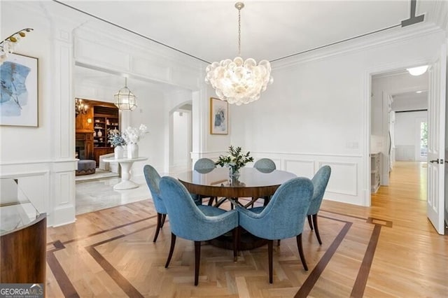 dining area featuring arched walkways, ornamental molding, and a decorative wall