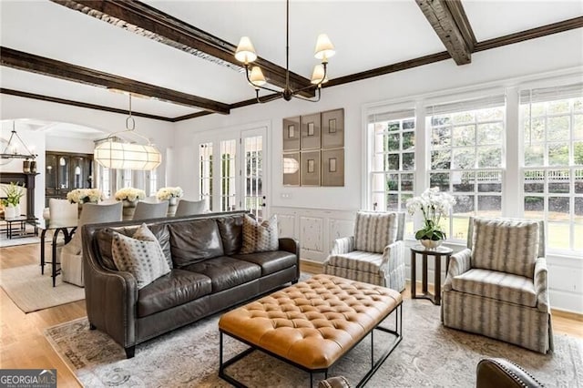 living room with beam ceiling, a healthy amount of sunlight, and an inviting chandelier