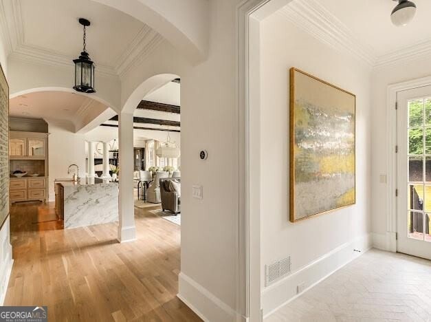 hall featuring ornamental molding, arched walkways, parquet floors, and baseboards