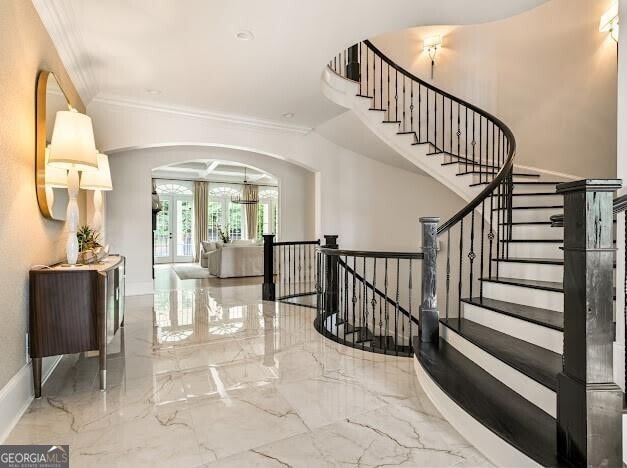 interior space featuring baseboards, arched walkways, ornamental molding, marble finish floor, and french doors