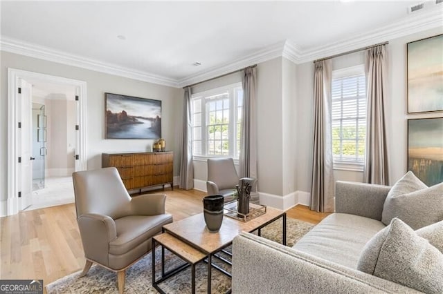 sitting room with ornamental molding, light wood-style flooring, a wealth of natural light, and baseboards