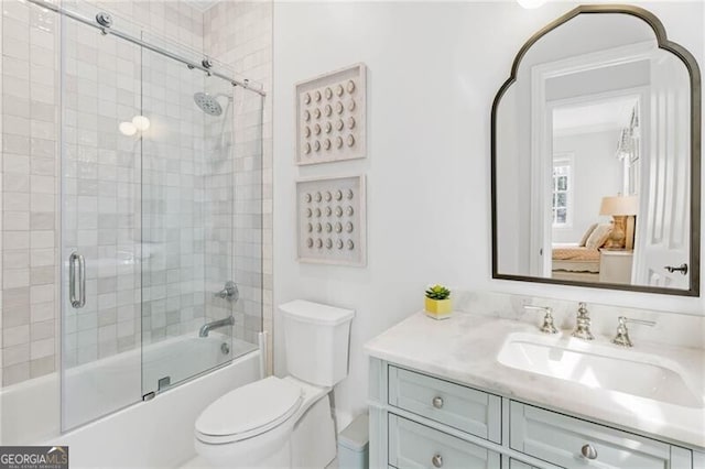 bathroom featuring toilet, bath / shower combo with glass door, and vanity