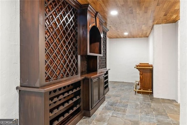 wine room with recessed lighting, wooden ceiling, and stone finish flooring