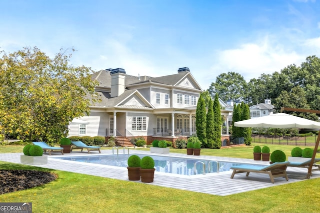 back of house with a chimney, a lawn, a patio area, fence, and an outdoor pool