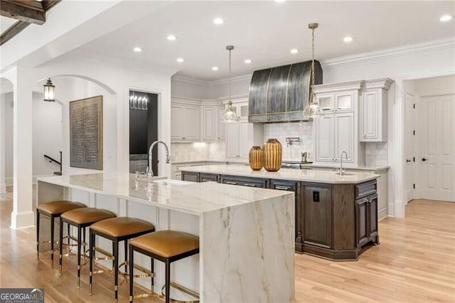 kitchen with arched walkways, a spacious island, and a sink