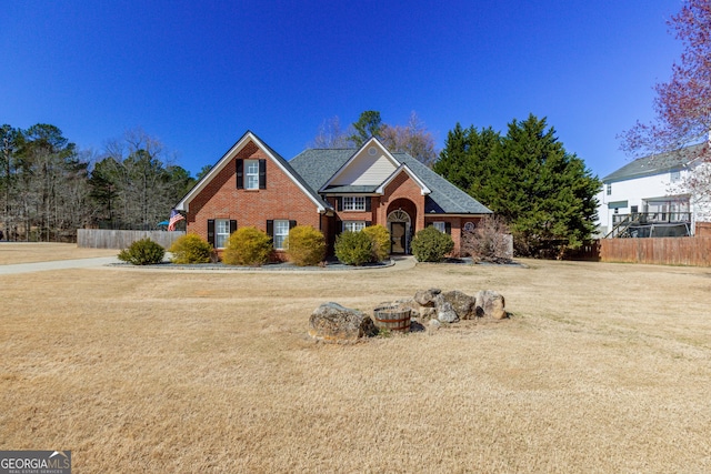 traditional-style house featuring fence and brick siding